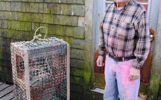 Dell, a longtime Bernard lobsterman, takes a break from painting his buoys. Photo by Alex Plummer/USHarbors.com.