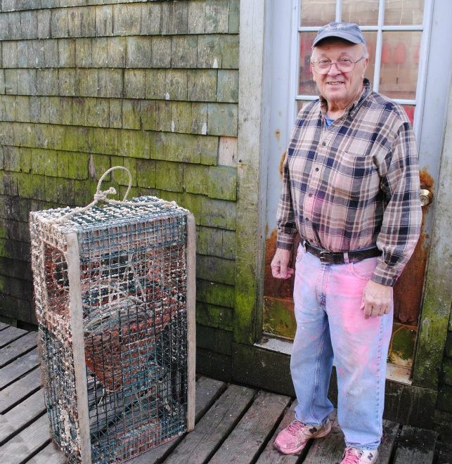 Dell, a longtime Bernard lobsterman, takes a break from painting his buoys. Photo by Alex Plummer/USHarbors.com.
