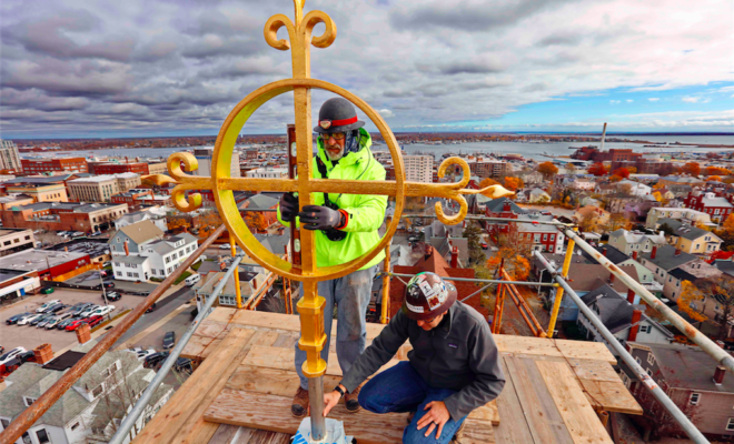 Pauly Reed and Michael Gnazzo install the new iron cross atop the Grace Episcopal Church on County Street in New Bedford, MA