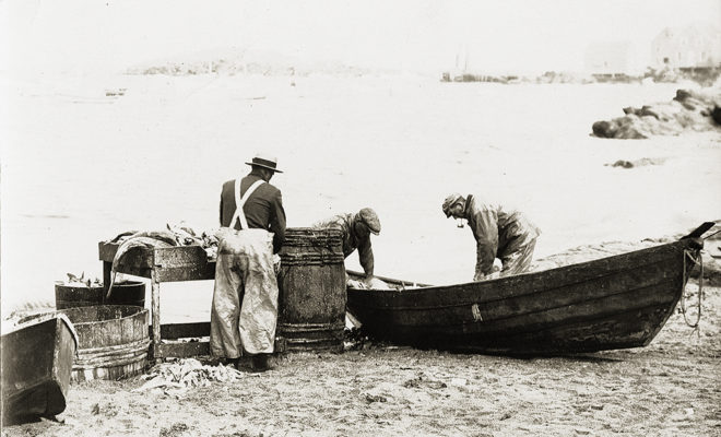 Monhegan Island, Maine — Fishermen cleaning catch out of a dory on the beach. From a postcard