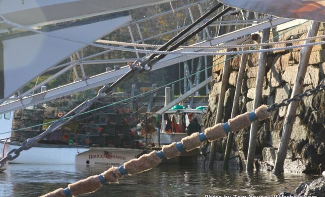 The view under a schooner's bow, as a lobsterboat unloads its traps.