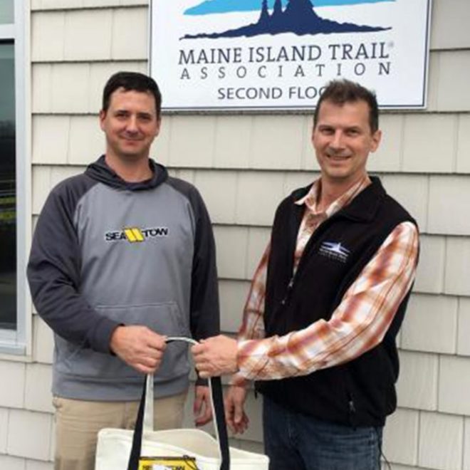 Sea Tow Portland/Midcoast co-owner Capt. Matt Wilder (left) provides a Sea Tow membership bag to MITA’s Exec Director Doug Welch