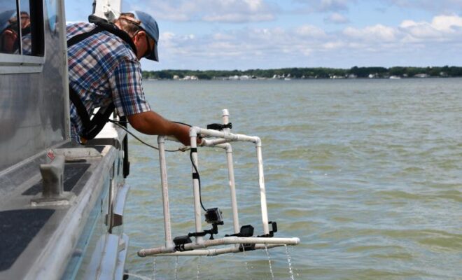 OysterVideoMonitoring, A NOAA scientist retrieves a frame on which a video camera is mounted from the water. NOAA is researching the use of video to track the progress of oyster reef restoration projects.
