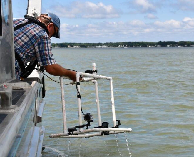 OysterVideoMonitoring, A NOAA scientist retrieves a frame on which a video camera is mounted from the water. NOAA is researching the use of video to track the progress of oyster reef restoration projects.