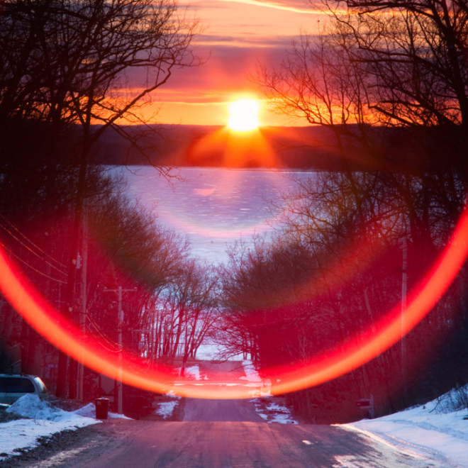 Sunset on a road with frozen lake in front. Image from Canva.com