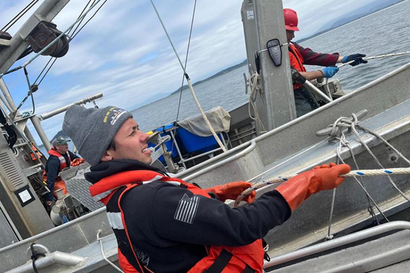 Image Credits: Former NOAA veteran intern Garret Engelke pulls in a surface trawling net on the Puget Sound with NOAA scientists.
