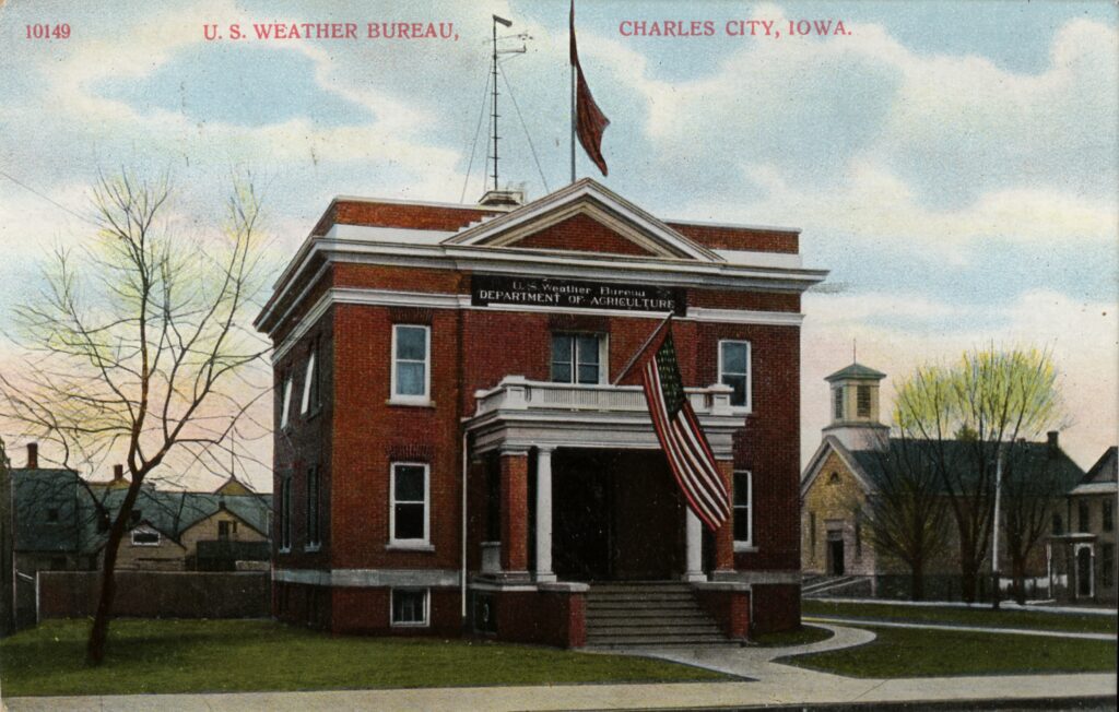 Image Credits: Postcard of the U.S. Weather Bureau Building at Charles City, Iowa. c. 1900. Note the Weather Forecast Flag system flags flown on the flag pole mounted on the roof. They appear to be the blue flag with a black pennant above, indicating a forecast of higher temperatures and rain. (Image credit: Courtesy of Steve Doty, NOAA NCDC (ret.))