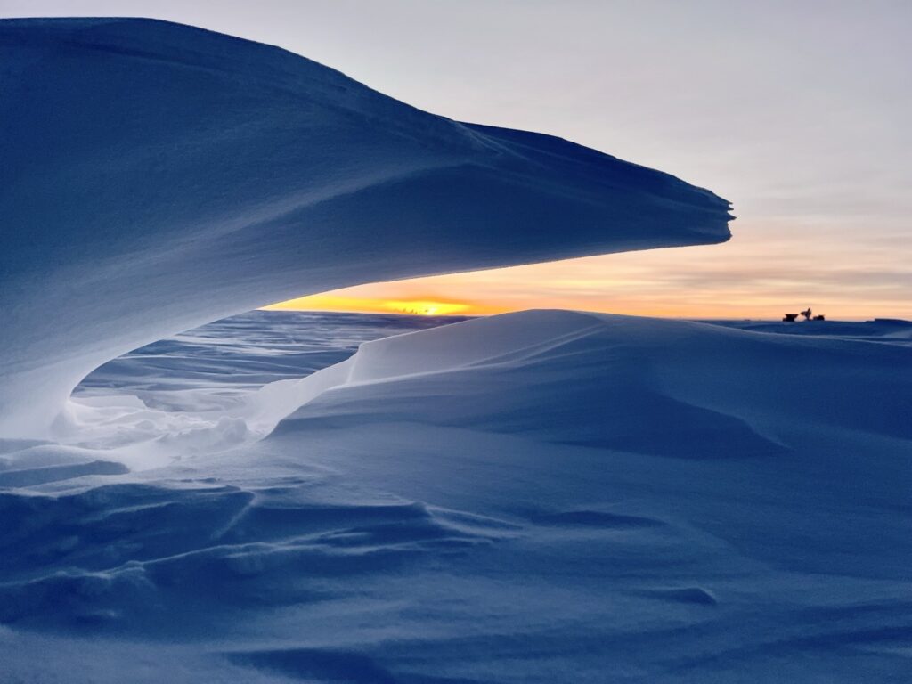 Image Credits: MARCH 20, 2025: At NOAA's South Pole Atmospheric Baseline Observatory, a wave of snow frames Dark Sector telescopes, giving a final glimpse of sunlight before six months of darkness. (Image credit: Ian Crocker/NOAA)