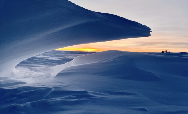Image Credits: MARCH 20, 2025: At NOAA's South Pole Atmospheric Baseline Observatory, a wave of snow frames Dark Sector telescopes, giving a final glimpse of sunlight before six months of darkness. (Image credit: Ian Crocker/NOAA)