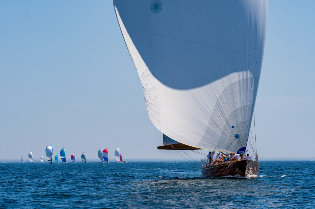 A sailboat leads the fleet on a downwind leg. Spinnakers flying