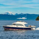aspen catamaran running along the coast of washington state with snow-capped mountains in the distance.