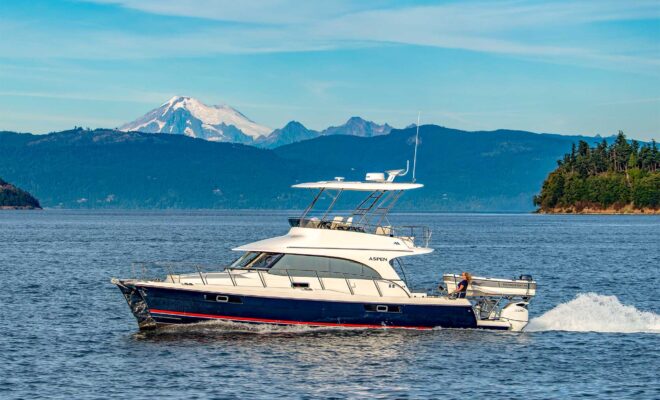 aspen catamaran running along the coast of washington state with snow-capped mountains in the distance.