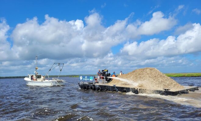 Project team staff operate a water cannon to distribute oyster shells across the project area. Credit: Justine Lundsted/NOAA