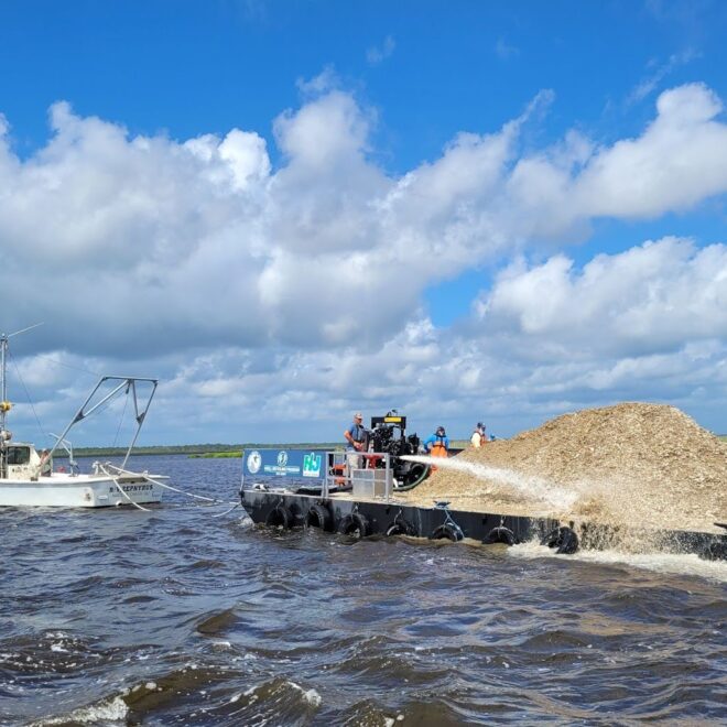 Project team staff operate a water cannon to distribute oyster shells across the project area. Credit: Justine Lundsted/NOAA