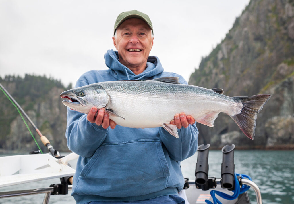 Fisherman holding up a salmon in Alaska
