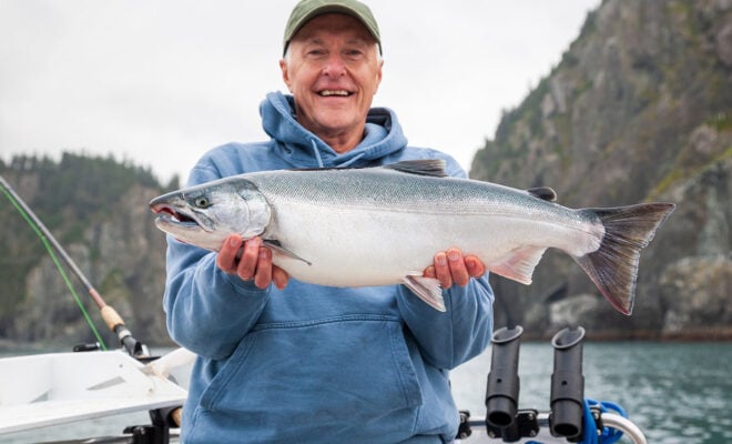 Fisherman holding up a salmon in Alaska