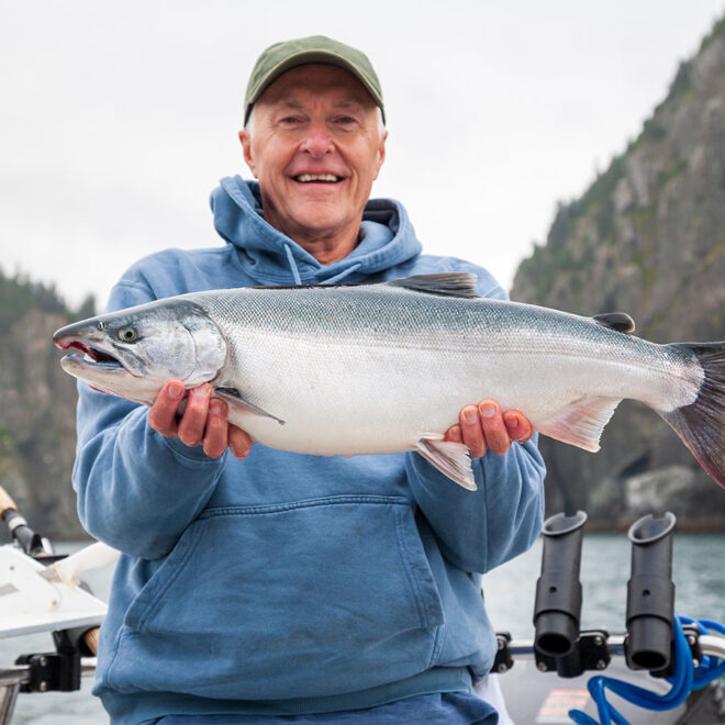 Fisherman holding up a salmon in Alaska