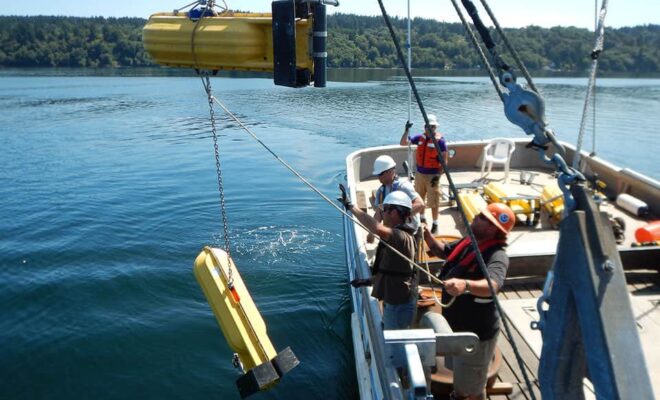 A NOAA team deploys a current meter with surface floats to take measurements throughout the water column during surveys of Puget Sound.