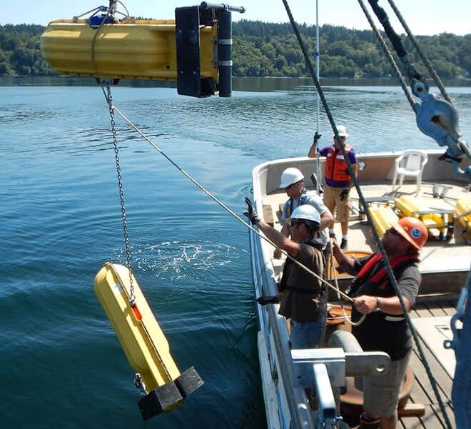 A NOAA team deploys a current meter with surface floats to take measurements throughout the water column during surveys of Puget Sound.