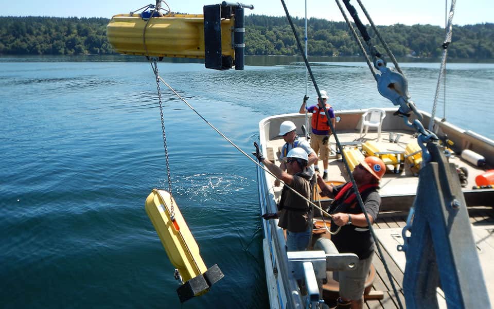 A NOAA team deploys a current meter with surface floats to take measurements throughout the water column during surveys of Puget Sound.