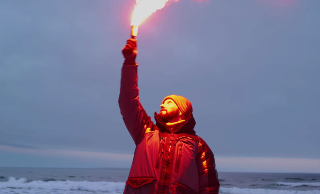 Fisherman firing red maritime distress signal flare. This type of signal flare is being replaced by new LED signal devices. Photo Shutterstock, TommyStockProject