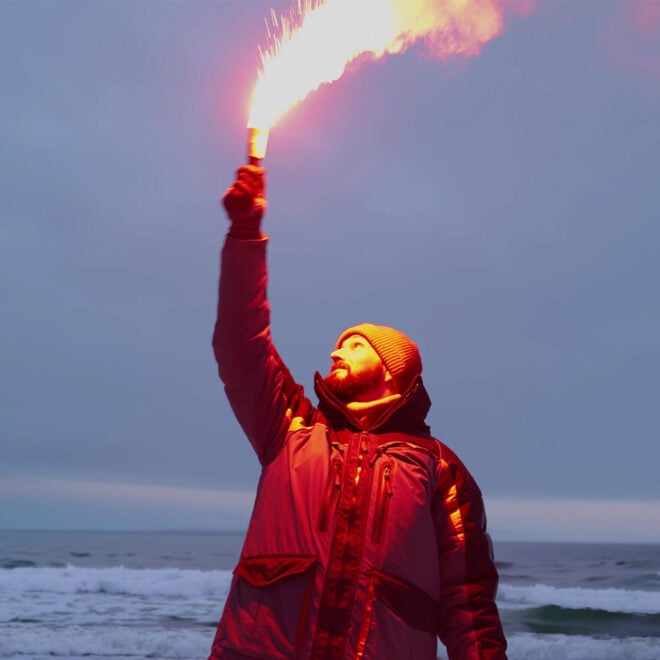 Fisherman firing red maritime distress signal flare. This type of signal flare is being replaced by new LED signal devices. Photo Shutterstock, TommyStockProject