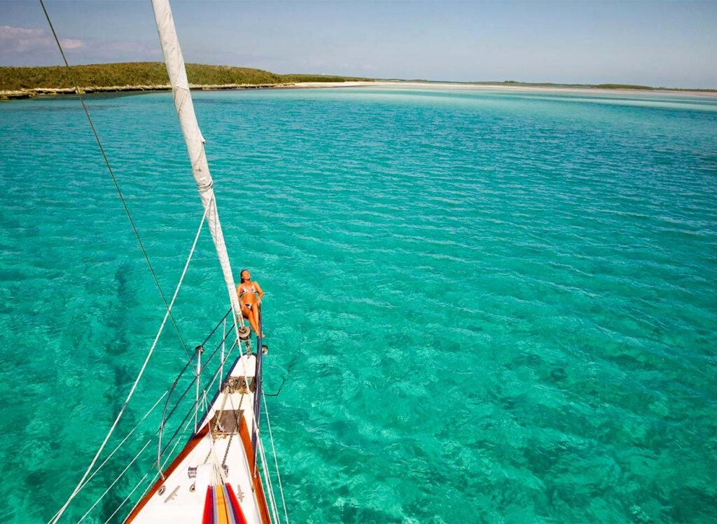 Sailboat at anchor in a cove, blue green water.
