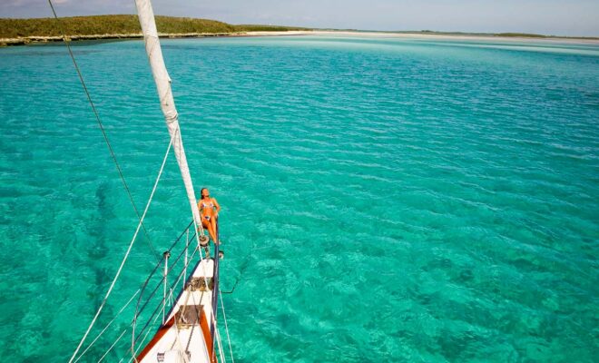 Sailboat at anchor in a cove, blue green water.