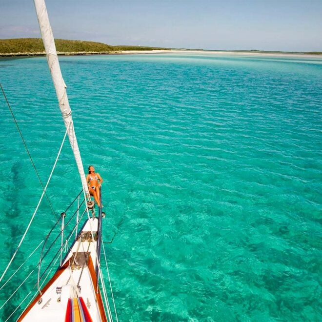 Sailboat at anchor in a cove, blue green water.