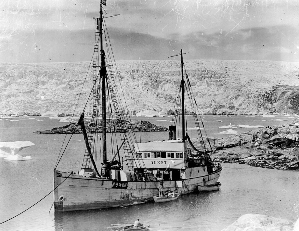A black and white photo of Sir Ernest Shackleton's ship, Quest, with a glacier in the background