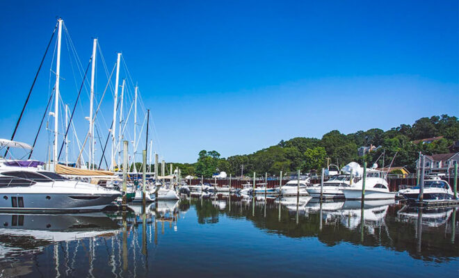 Boats at the docks of a marina, reflecting in the calm water