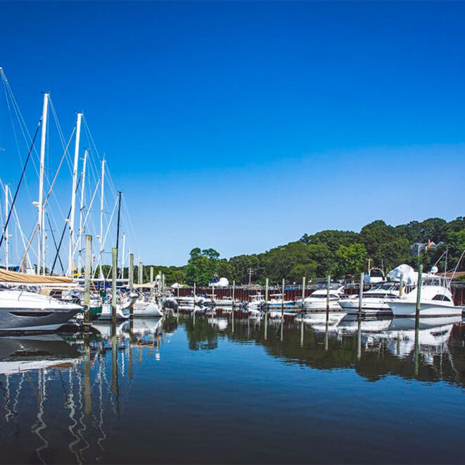 Boats at the docks of a marina, reflecting in the calm water