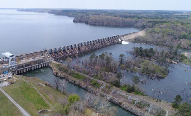 Roanoke Rapids Dam on the Roanoke River in North Carolina. The powerhouse and spillway are to the left, the bypassed reach of the river is on the right. On the right side of the dam, water is flowing over the spillway and into the bypassed reach. Credit: Dominion Energy.