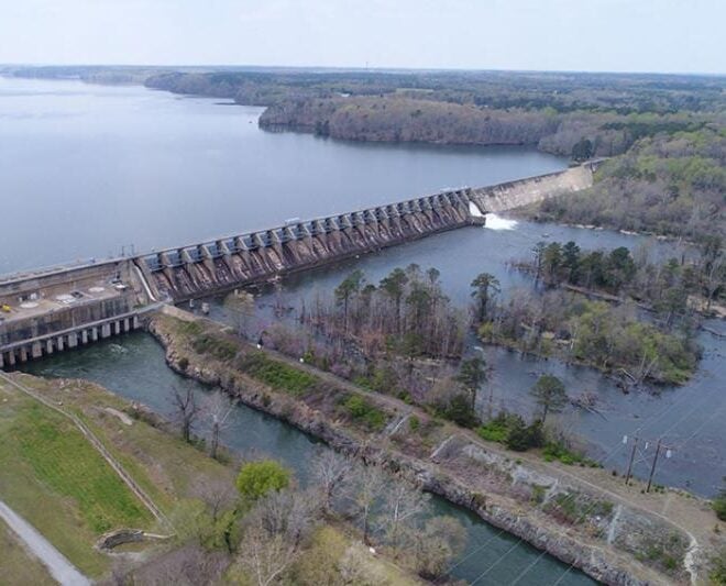 Roanoke Rapids Dam on the Roanoke River in North Carolina. The powerhouse and spillway are to the left, the bypassed reach of the river is on the right. On the right side of the dam, water is flowing over the spillway and into the bypassed reach. Credit: Dominion Energy.