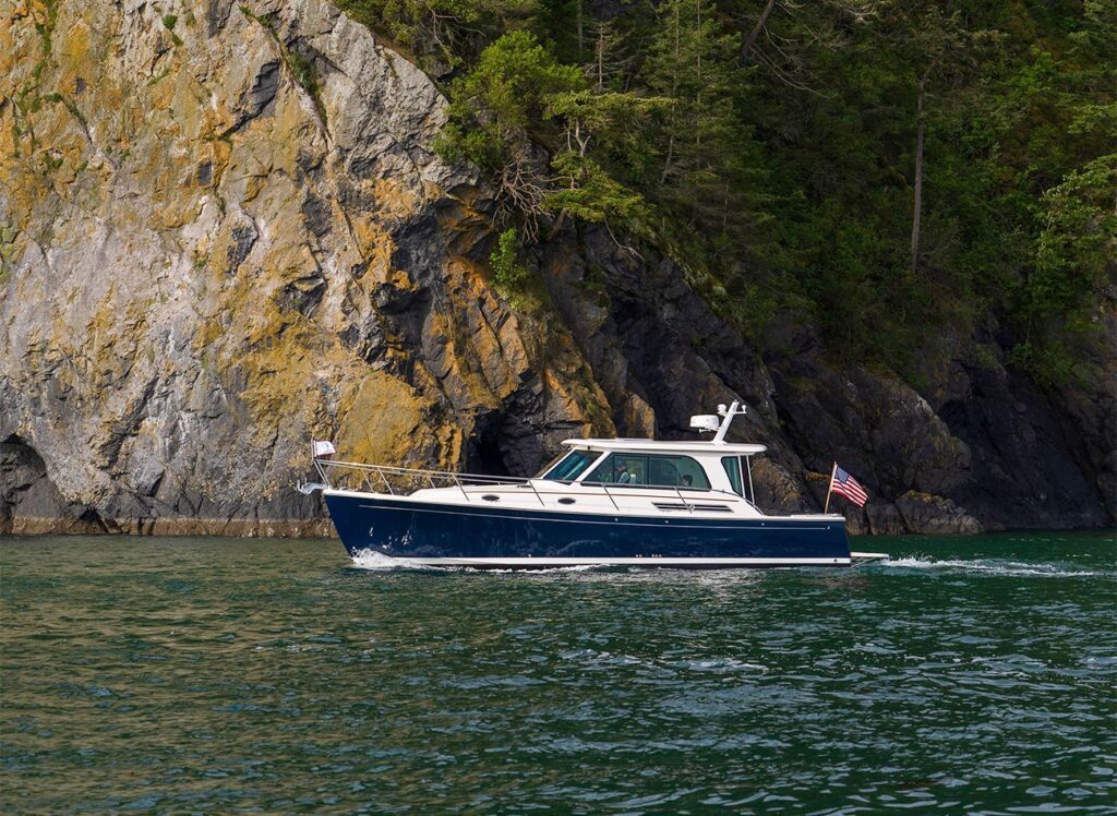 A blue powerboat motoring past an island with a rocky coastline