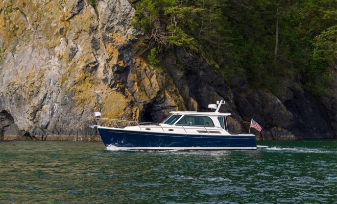 A blue powerboat motoring past an island with a rocky coastline