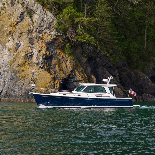 A blue powerboat motoring past an island with a rocky coastline