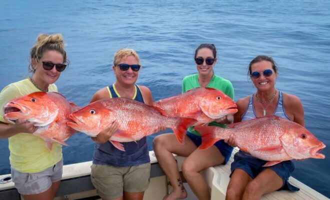 A group of women aboard a boat hold large red snappers caught during a recreational fishing trip. Credit: Grayson Shepard