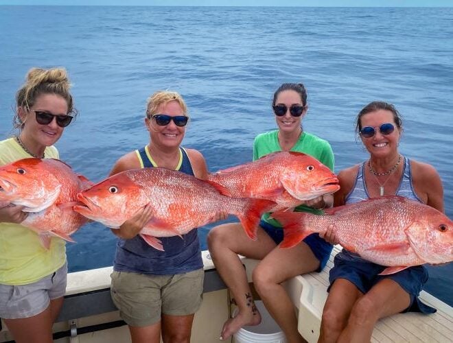 A group of women aboard a boat hold large red snappers caught during a recreational fishing trip. Credit: Grayson Shepard
